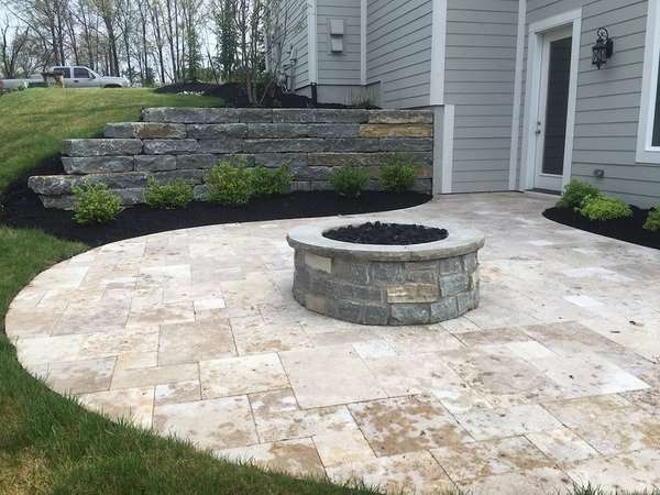 Stone retaining wall by patio with stone fire pit built by Freedom Stone + Pondscapes