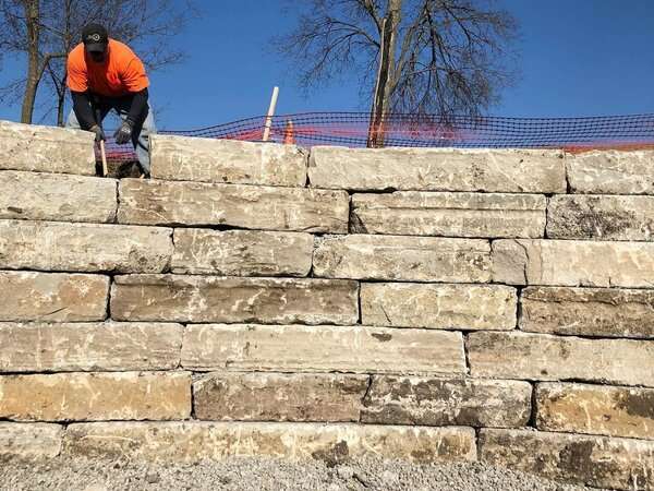 Freedom Stone + Pondscapes employee leveling a stone retaining wall