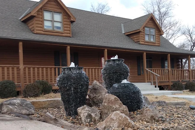 Three urn stacked slate urn fountains in front of a wood house