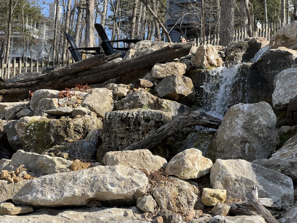 Rocky waterfall with surrounding trees and chairs.