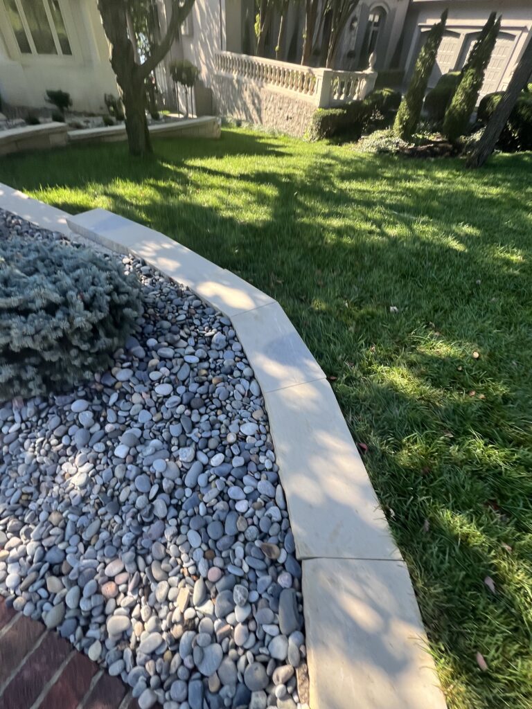 Residential garden with grass and decorative stone border.