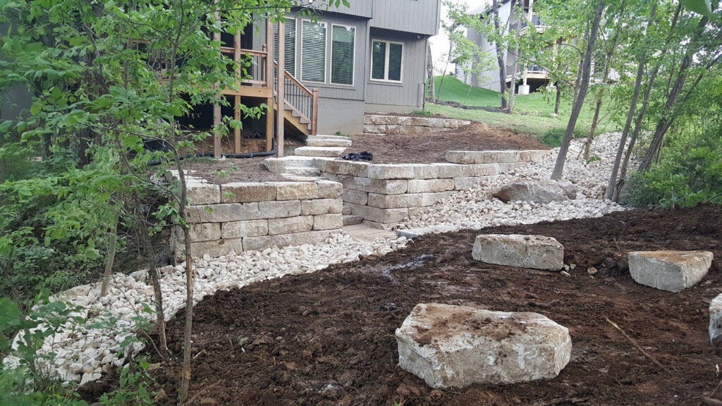 Stone retaining wall construction in backyard landscape.